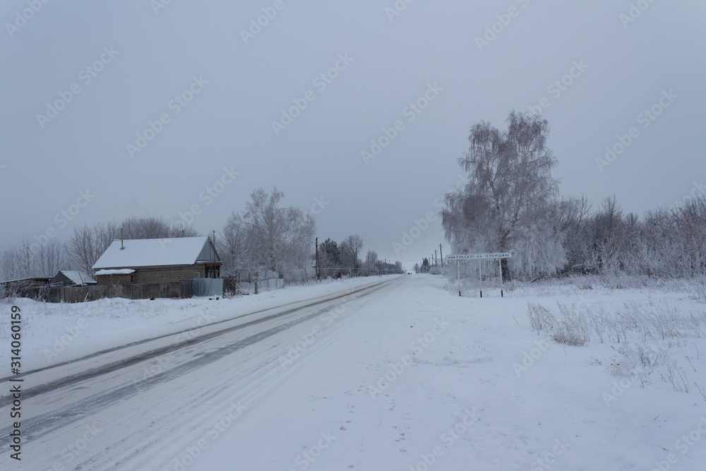 A snow-covered house and trees on the outskirts of a Russian village, the inscription 