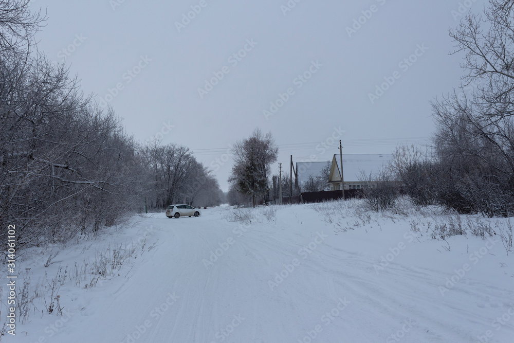 The outskirts of the Russian village of Nikolskoye-on-Cheremshan, winter rural road and forest, winter evening in the Ulyanovsk region in Russia.