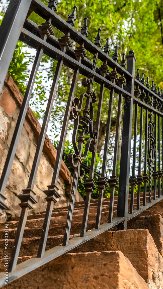Vertical frame Close up of metal railing and stone treads of a staircase against stone fence Vertical frame Close up of metal railing and stone treads of a staircase against stone fence