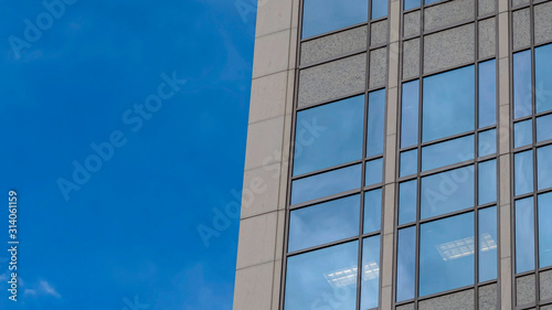 Pano frame Focus on a modern building exterior with glass windows reflecting the blue sky