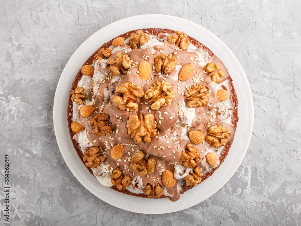 Homemade cake with milk cream, cocoa, almond, hazelnut on a gray concrete background with orange textile. Top view. Homemade cake with milk cream, cocoa, almond, hazelnut on a gray concrete background with orange textile. Top view.