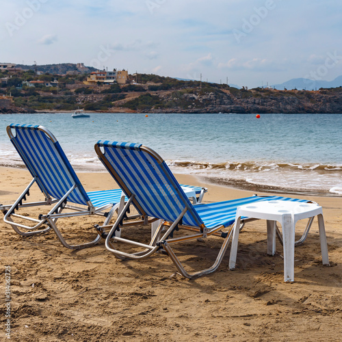 two sun loungers on the sandy beach of the Greek resort town of Agios Nikolaos