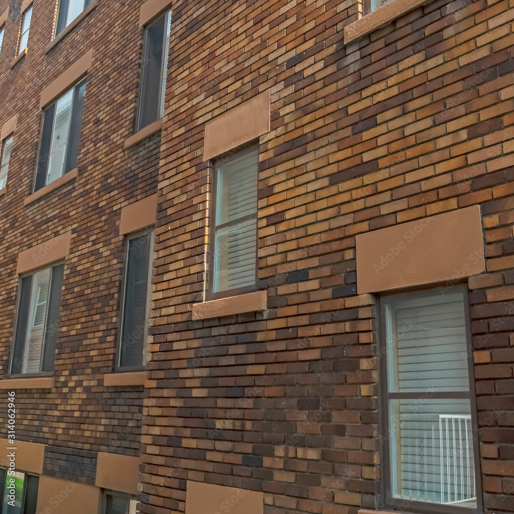 Square Exterior of an old classic building with brick wall and windows with gray frames Square Exterior of an old classic building with brick wall and windows with gray frames