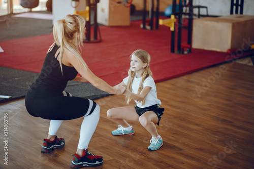 Beautiful woman in the gym. A family performs exercises.