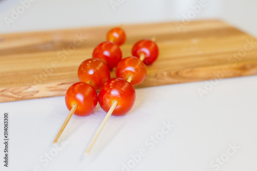 cherry tomatoes on skewers on a wooden Board, on a white background. texture. concept of fresh vegetables and healthy food. BBQ. space for text. top view of tomatoes. ripe harvest.