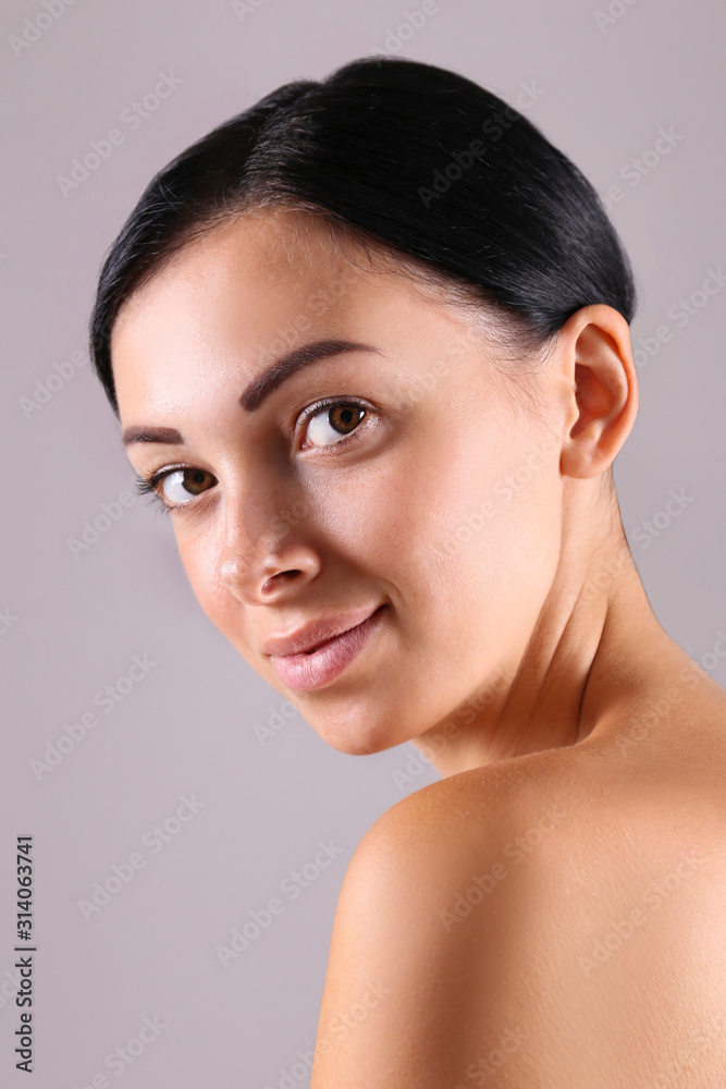 Portrait of young beautiful woman with perfectly clean face skin. Female with long black hair tied in ponytail smiling showing skincare results. Close up, copy space background. Portrait of young beautiful woman with perfectly clean face skin. Female with long black hair tied in ponytail smiling showing skincare results. Close up, copy space background.
