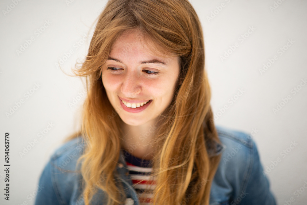 Close up smiling young woman looking down by white background Close up smiling young woman looking down by white background