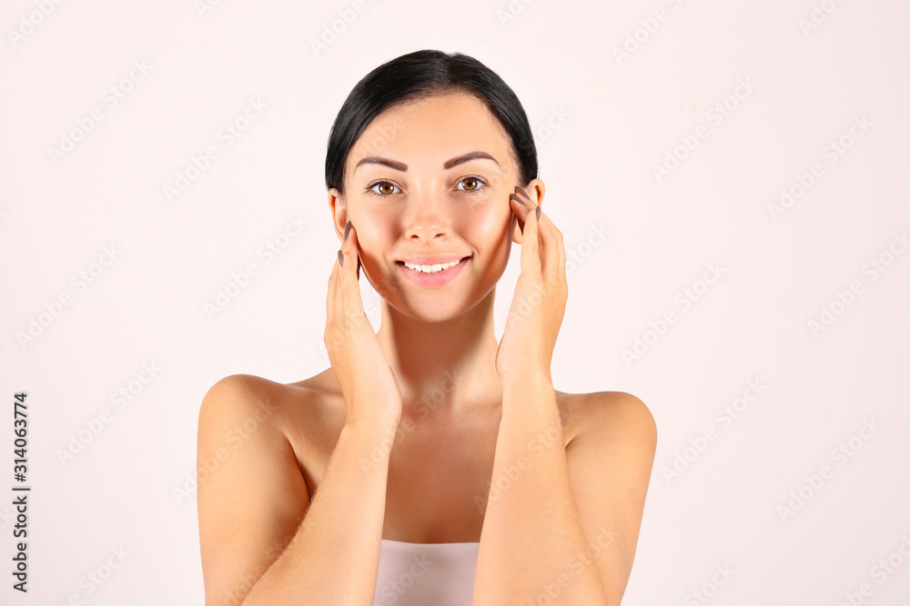 Portrait of young beautiful woman with perfectly clean face skin. Female with long black hair tied in ponytail smiling showing skincare results. Close up, copy space background. Portrait of young beautiful woman with perfectly clean face skin. Female with long black hair tied in ponytail smiling showing skincare results. Close up, copy space background.