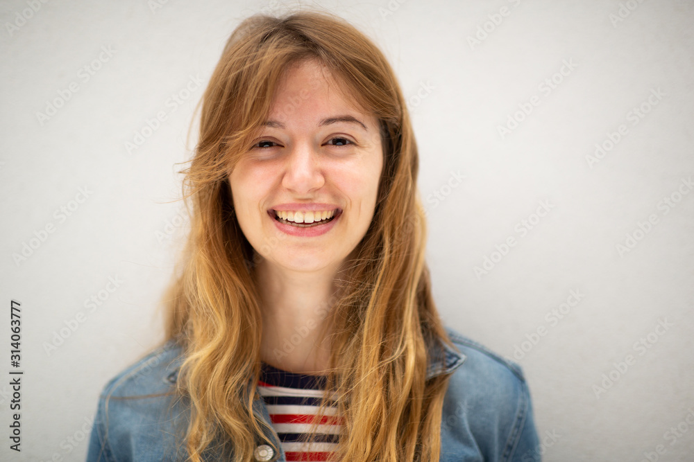 Close up portrait of young woman with long blond hair smiling by white background