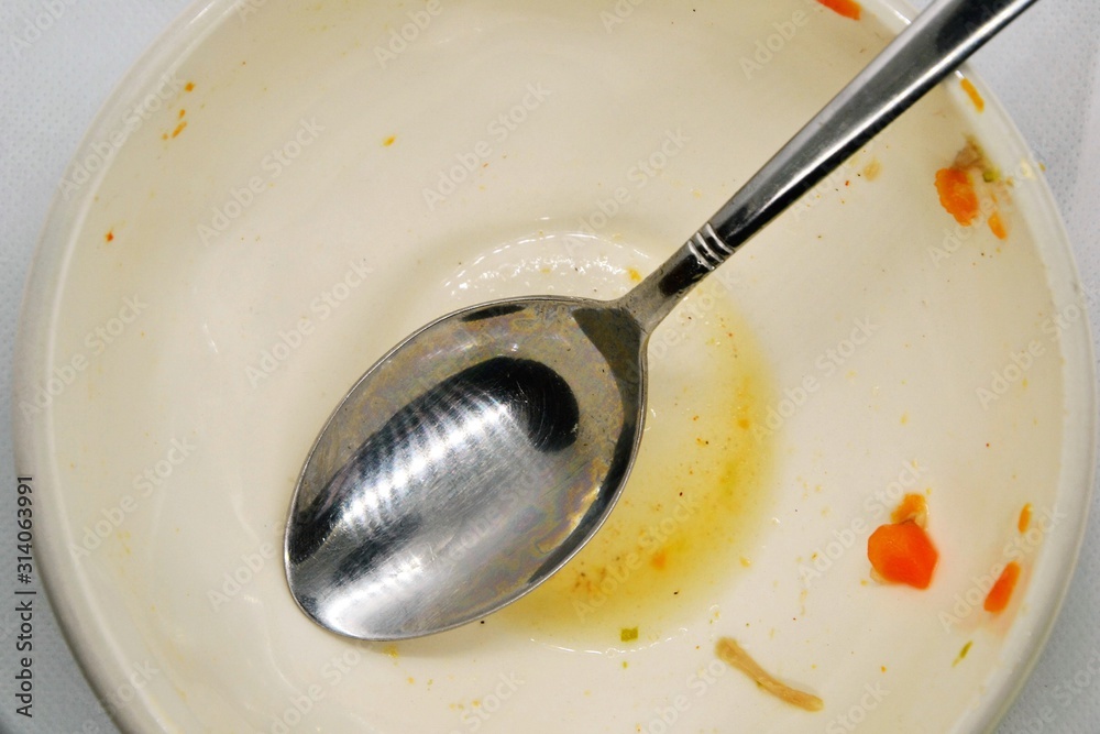 Empty bowl. Dirty, empty bowl with spoon. After meal. Top view. Dirty bowl with food leftovers Empty bowl. Dirty, empty bowl with spoon. After meal. Top view. Dirty bowl with food leftovers