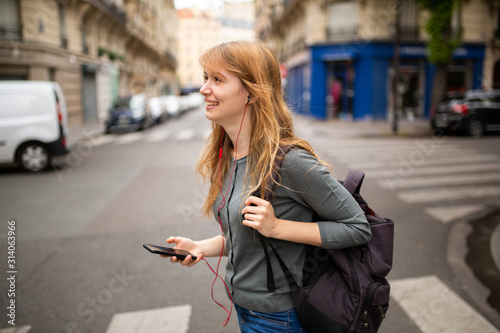 young woman crossing the street listening to music with mobile phone and earphones