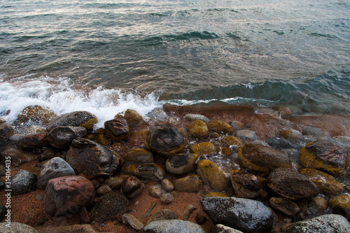 Stones on the sea beach. Pasture winter day. Clear water and sand. Kyrgyzstan, Issyk-Kul Lake