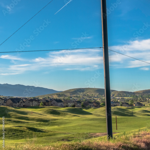 Square frame Fence with scenic view of golf course houses and mountain on a sunny day