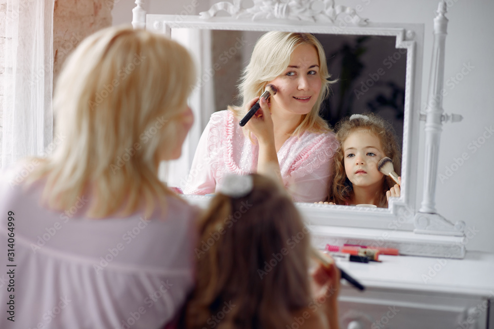 Family sitting infront a mirror. Mother in a pink pajamas. Little girl with cosmetics. Family sitting infront a mirror. Mother in a pink pajamas. Little girl with cosmetics.