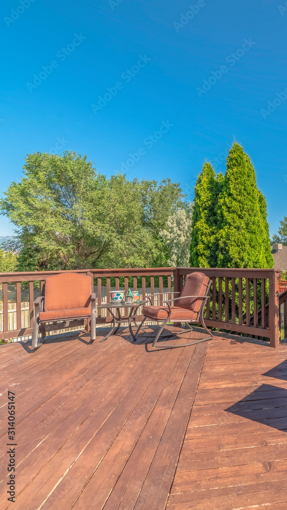 Vertical frame Balcony with furniture and stairs overlooking trees and blue sky on a sunny day Vertical frame Balcony with furniture and stairs overlooking trees and blue sky on a sunny day