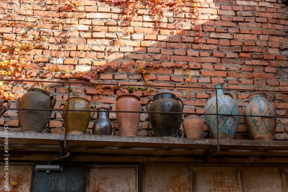 shelf with old earthenware jars on a brick wall shelf with old earthenware jars on a brick wall