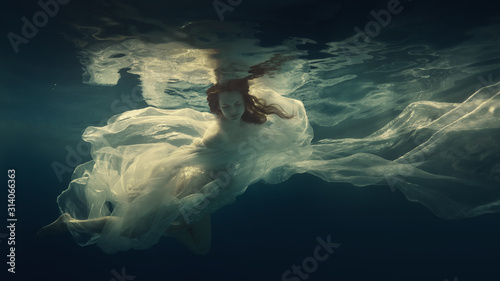 Portrait of a girl in a dress floating underwater