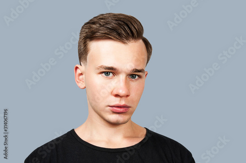 portrait white young guy model dressed in black t shirt looking at the camera on isolaed background