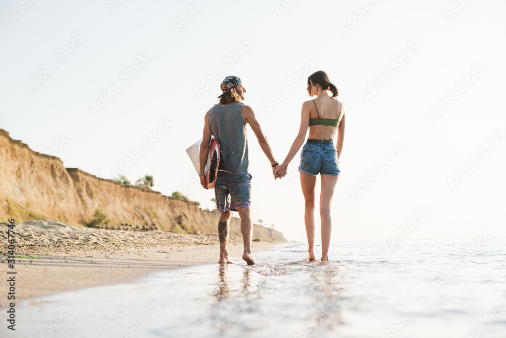 Photo from back of young couple holding hands together Photo from back of young couple holding hands together