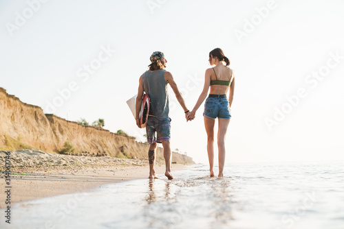 Photo from back of young couple holding hands together