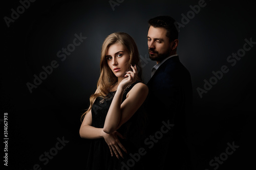 elegant couple on black background. handsome man and beautiful woman in black dress