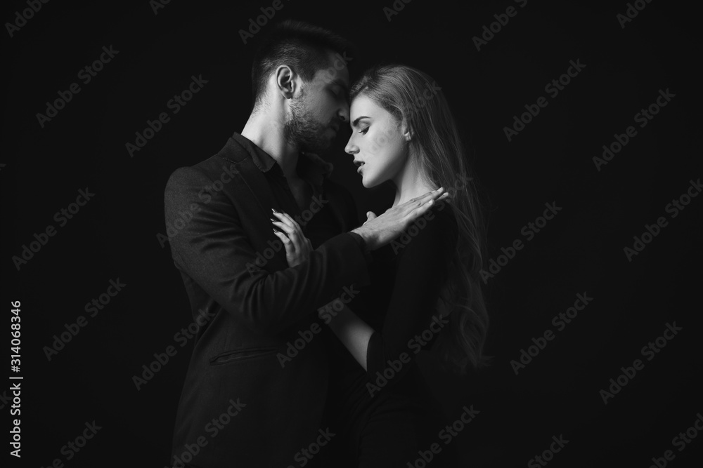 elegant couple in the tender passion. man embracing beautiful woman in black dress. black and white elegant couple in the tender passion. man embracing beautiful woman in black dress. black and white