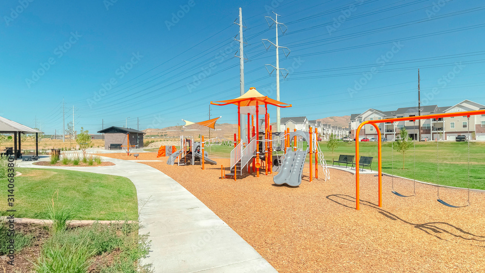 Pano Swings and slides at a playground with pathways and pavilion against blue sky Pano Swings and slides at a playground with pathways and pavilion against blue sky