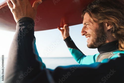 Photography Photo of handsome smiling man surfboard on his head