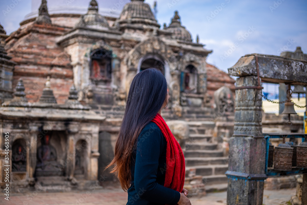 Young girl standing infront of a Sacred Buddhist Monastery. Sculptures of Gods and Goddesses carved on the stone of Ancient Buddhist Temple and ancient ruins. Intricate Details.