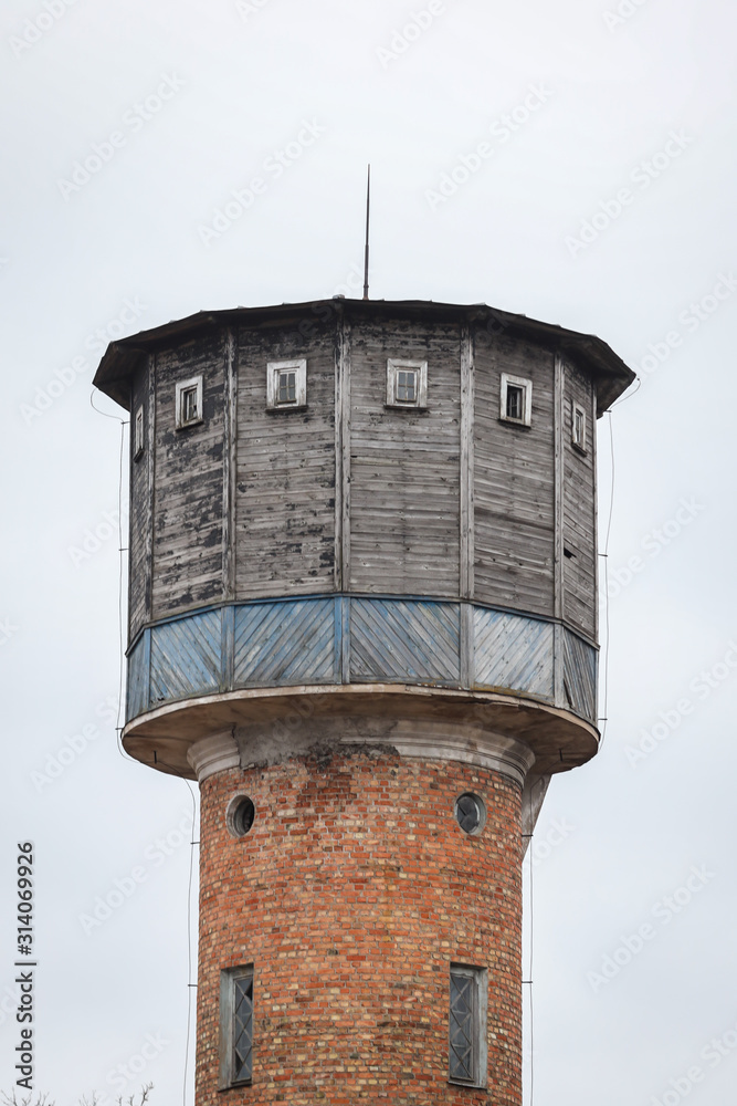 Old brick watertower with wood top, located in small countryside city centre.