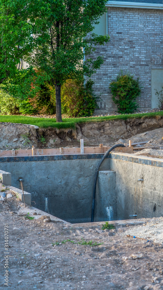 Vertical frame Construction of a residential swimming pool with houses and trees background Vertical frame Construction of a residential swimming pool with houses and trees background