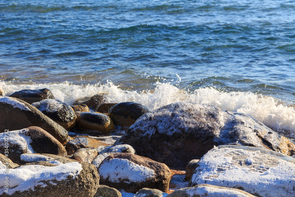 Stones on the sea beach. Pasture winter day. Clear water and sand. Kyrgyzstan, Issyk-Kul Lake Stones on the sea beach. Pasture winter day. Clear water and sand. Kyrgyzstan, Issyk-Kul Lake