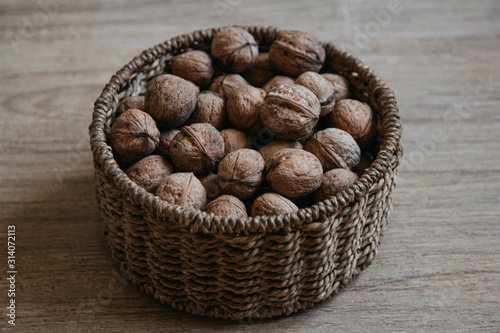 Walnuts in a round wicker basket on a wooden background. Top view. Copy, empty space for text.