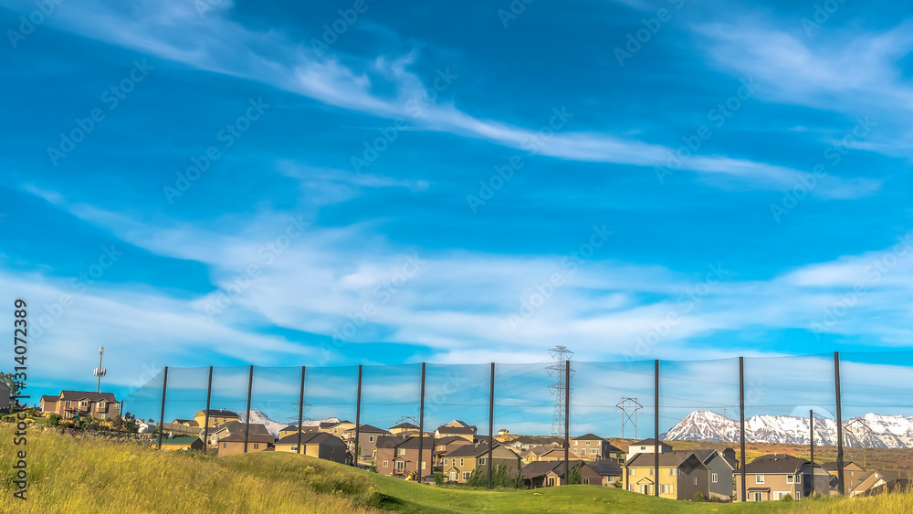 Pano frame Golf course fence with homes and snow capped mountain in the scenic background
