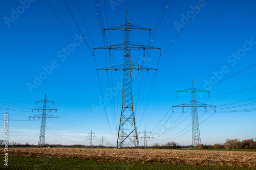 Eine Reihe Strommasten vor blauem Himmel auf braunem Feld