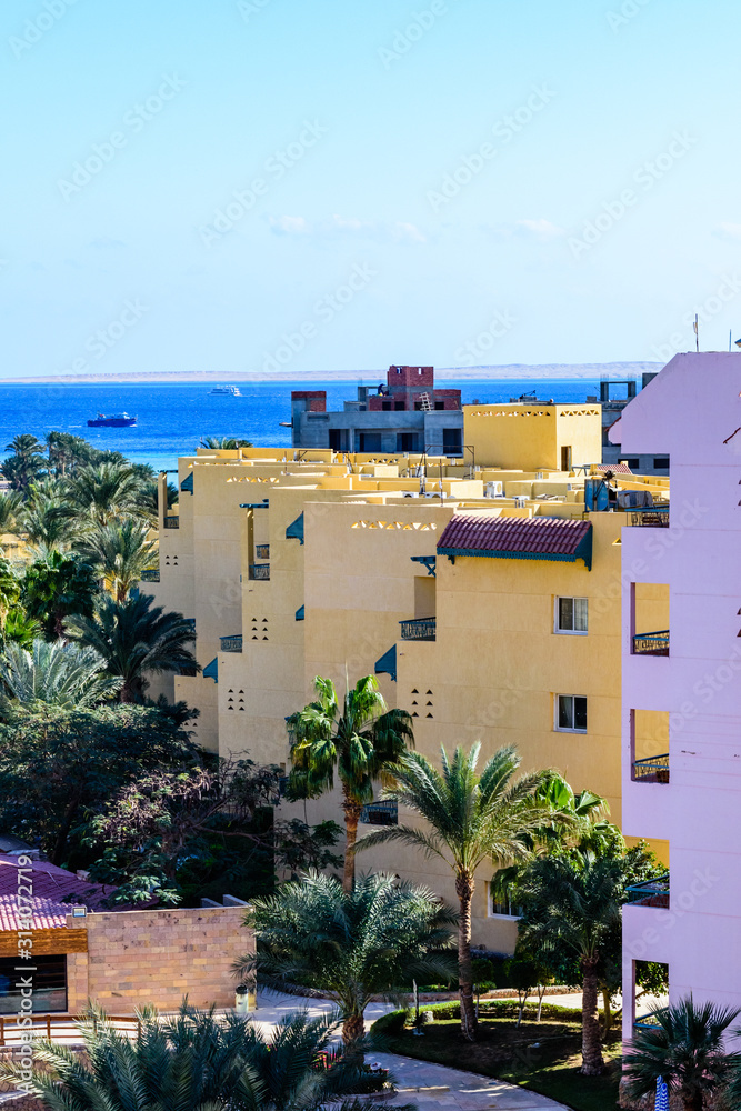 View on a buildings, green palm trees and Red sea