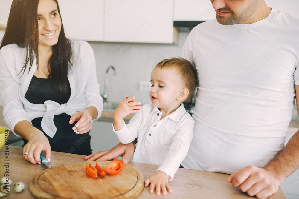 Family in a kitchen. Beautiful mother with little son. Father in a white t-shirt.