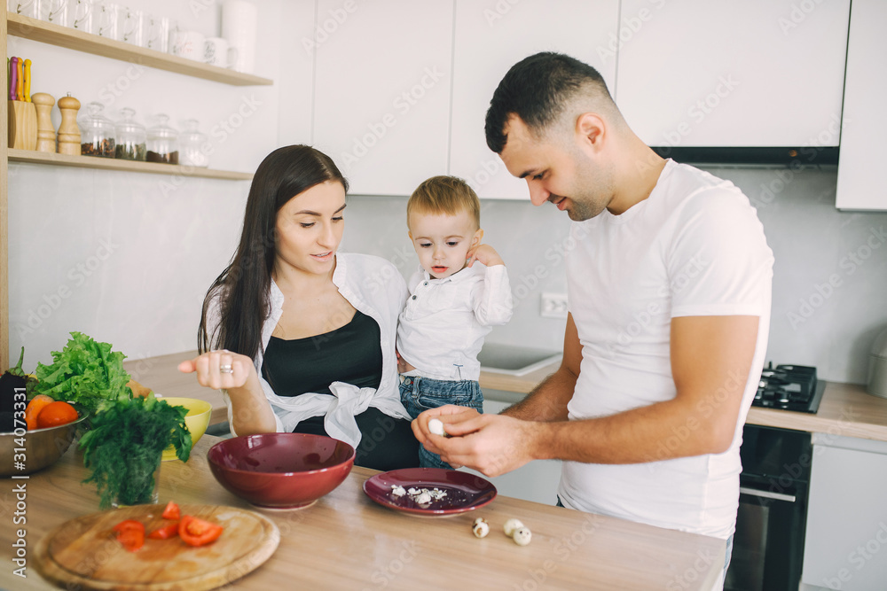 Family in a kitchen. Beautiful mother with little son. Father in a white t-shirt. Family in a kitchen. Beautiful mother with little son. Father in a white t-shirt.