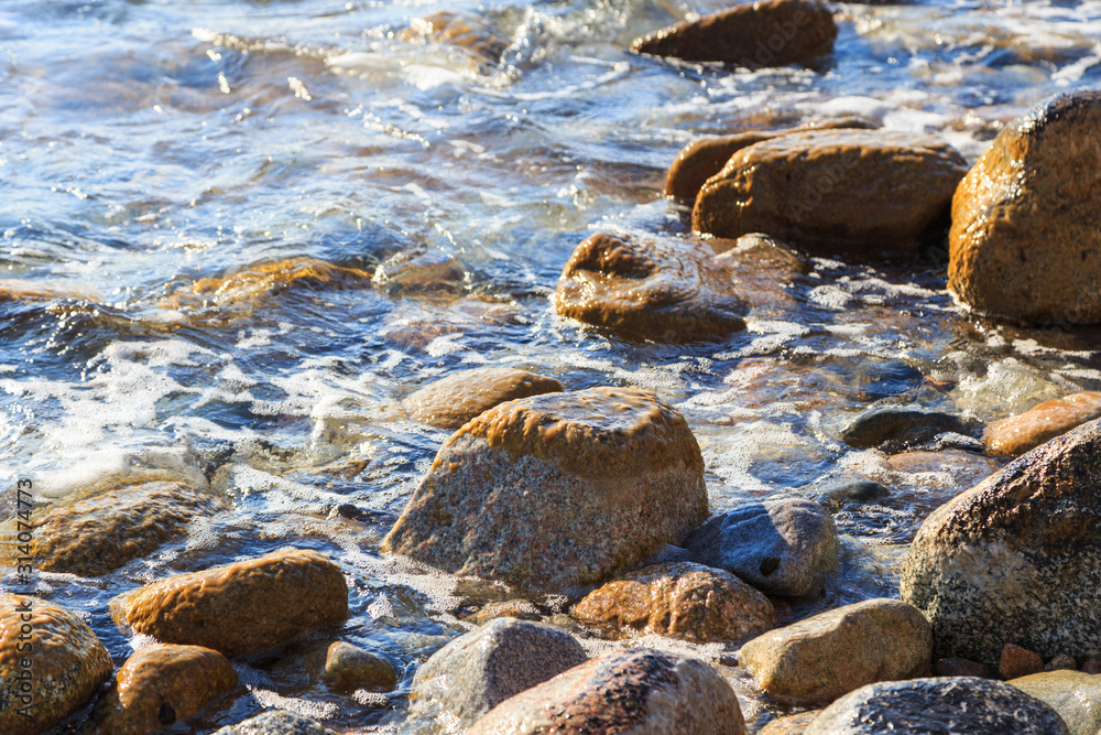 Stones on the sea beach. Pasture winter day. Clear water and sand. Kyrgyzstan, Issyk-Kul Lake Stones on the sea beach. Pasture winter day. Clear water and sand. Kyrgyzstan, Issyk-Kul Lake