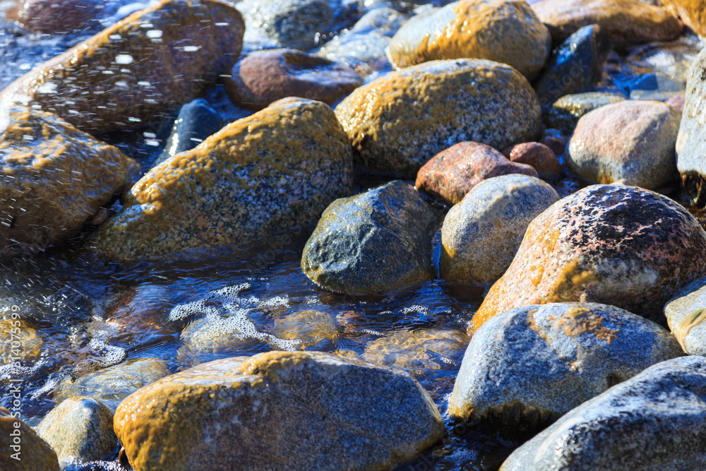 Stones on the sea beach. Pasture winter day. Clear water and sand. Kyrgyzstan, Issyk-Kul Lake Stones on the sea beach. Pasture winter day. Clear water and sand. Kyrgyzstan, Issyk-Kul Lake