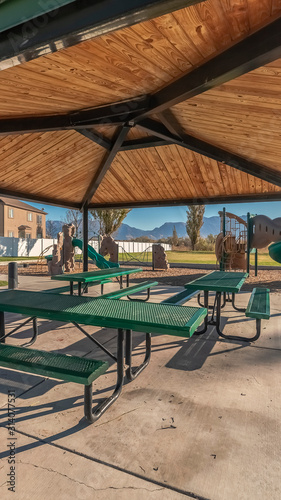 Vertical Empty green tables and benches in an urban park © Jason