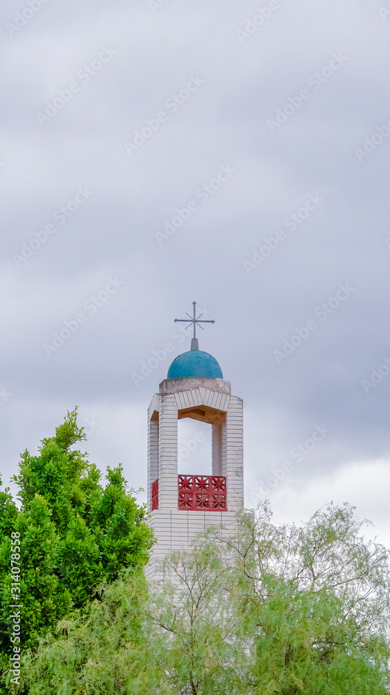 Vertical Bell Tower of a church rising above green trees