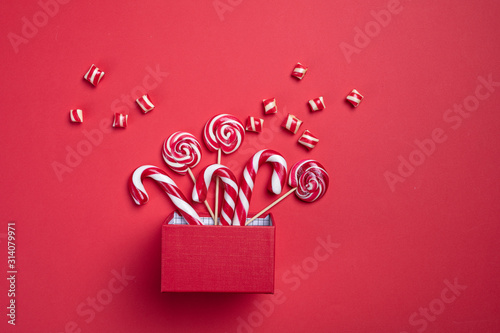 Christmas card. Invitation card on a red background. Surprise box with sweets. Interesting proposition for you. photo