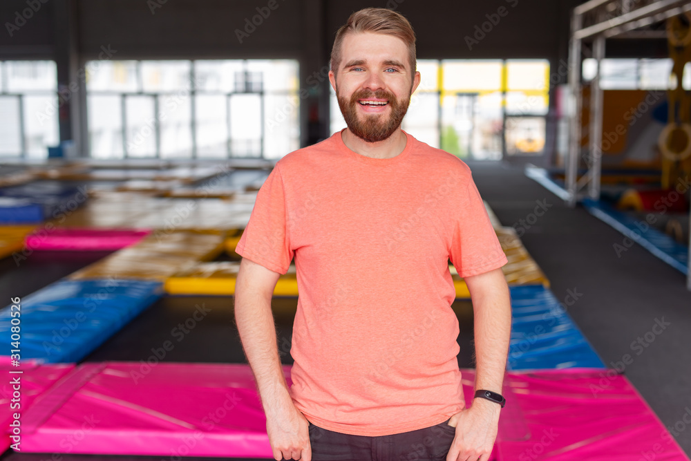 Fitness, fun, leisure and sport activity concept - Man smiling on a trampoline indoors Fitness, fun, leisure and sport activity concept - Man smiling on a trampoline indoors