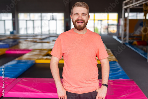 Fitness, fun, leisure and sport activity concept - Man smiling on a trampoline indoors