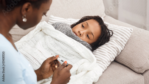 Slika na platnu Afro mom checking temperature of her ill daughter