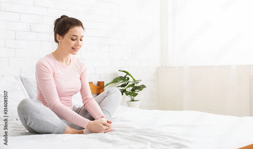 Positive woman warming up her legs on bed, panorama Positive woman warming up her legs on bed, panorama