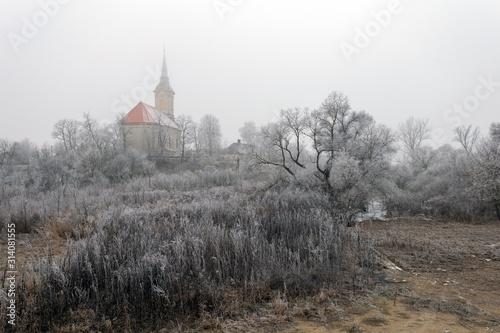 Fototapeta Naklejka Na Ścianę i Meble -  Frosty trees and bushes around the church of  Sajopuspoki on a winter day