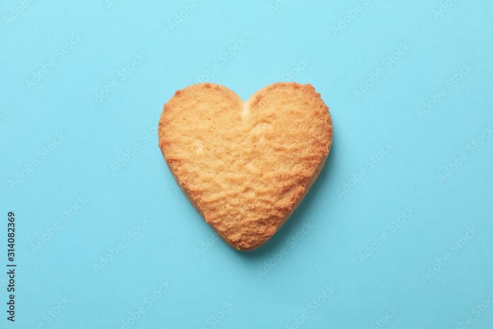 Heart shaped cookie on blue background, close up Heart shaped cookie on blue background, close up