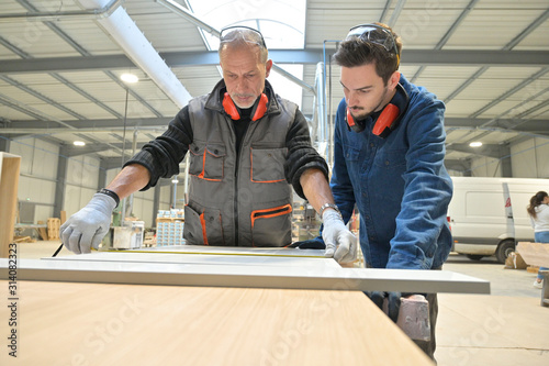 Carpenter with apprentice working in workshop
